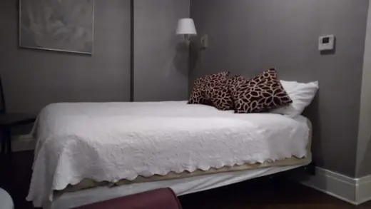 Cozy bedroom with a white quilt and decorative pillows at Kevin Guest House, a sober living home in Buffalo.